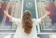 年轻的女人国际机场飞行信息董事会检查飞行