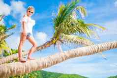 可爱的女孩热带海滩棕榈树夏天假期背景蓝色的天空