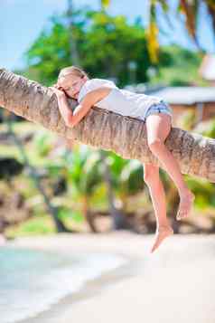 可爱的女孩热带海滩坐着棕榈树夏天假期