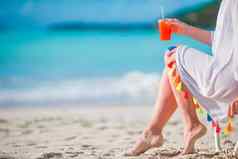 年轻的女人鸡尾酒玻璃白色海滩坐着日光浴浴床特写镜头美味的鸡尾酒背景海