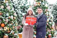 年轻的美丽的快乐的夫妇庆祝圣诞节城市街给礼物