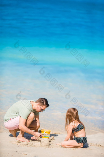 家庭使沙子城堡热带白色海滩父亲女孩玩沙子热带海滩