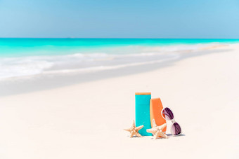 防晒霜瓶护目镜海星太阳镜白色沙子海滩背景海洋
