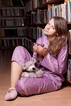 女孩紫色的睡衣玩具坐在架子上书