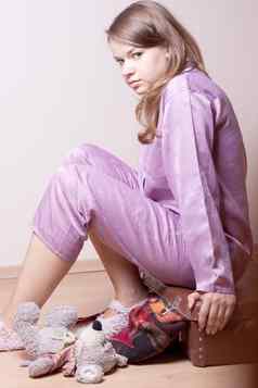 女孩紫色的睡衣坐着手提箱