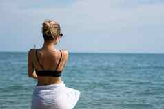 年轻的女人站海滩享受太阳年轻的女人比基尼海水海滩热带度假胜地后视图假期旅行概念