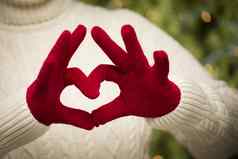 女人穿红色的连指手套持有心手标志