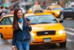 年轻的女人走纽约城市电话应用程序出租车骑称赞耳机通勤工作亚洲女孩快乐发短信智能手机城市走通勤纽约
