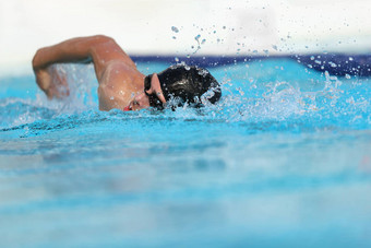 游泳池运动员培训在室内专业竞争游泳运动员男人。游泳实践体育场爬手臂溅水复制空间蓝色的水背景