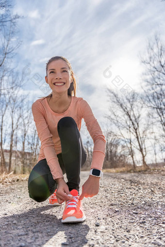 秋天小道跑步者亚洲女孩系运行鞋子穿体育智能手表小工具齿轮女活跃的运动员用带子束紧鞋鞋带森林路径聪明的看心率健身监控