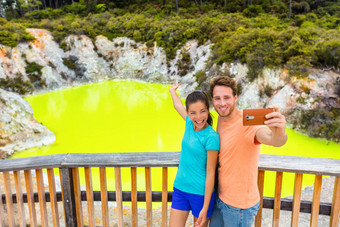 新西兰旅游吸引力夫妇游客采取自拍旅行目的地怀奥塔普活跃的地热绿色池塘罗托鲁瓦北岛wai-o-tapu新西兰