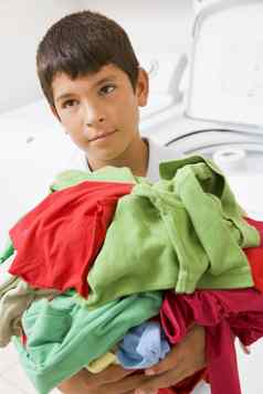 年轻的男孩持有桩洗衣