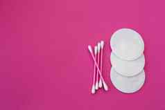 前视图粉红色的棉花味蕾白色头白色轮棉花磁盘铺设粉红色的背景