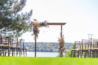 美丽的聚会地点露天婚礼仪式婚礼拱行客人椅子绿色草坪上俯瞰河