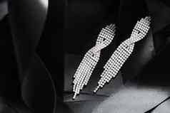 奢侈品钻石耳环黑色的丝绸丝带背景珠宝时尚品牌