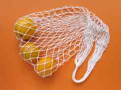 白色字符串棉花生态袋橙子橙色背景单色简单的平躺生态浪费概念股票照片