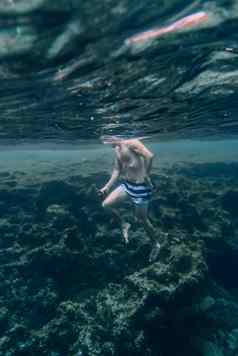 水下照片男人。男孩游泳岩石海海岸医护