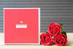 红色的玫瑰心形的盒子木背景