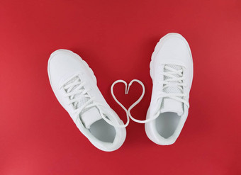 白色体育鞋子心形状鞋带红色的背景简单的平躺
