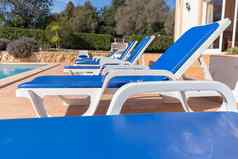 蓝色的缓冲帆布躺椅边缘游泳池夏天