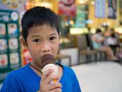男孩吃冰奶油内部购物中心模糊背景