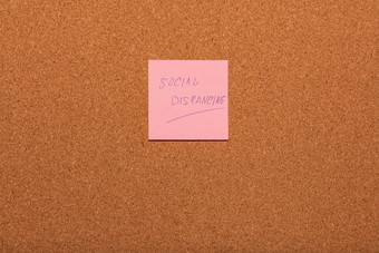 提醒社会距离手写的粉红色的贴纸软木塞通知栏