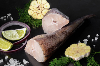 新鲜的<strong>冻鳕鱼</strong>尸体鱼角烹饪成分草本植物胡椒柠檬黑色的背景