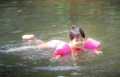 亚洲女孩穿充气袖子游泳自然