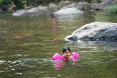 亚洲女孩穿充气袖子游泳自然
