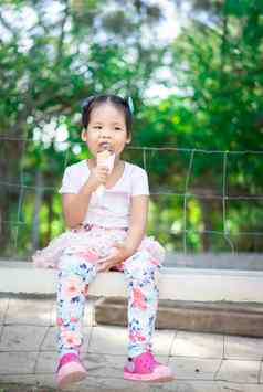 亚洲女孩吃冰奶油在户外自然利格