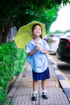 女孩泰国学校统一的黄色的伞raini