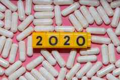前关闭拍摄白色药片周围黄色的多维数据集黑色的数字形式一年粉红色的背景医疗保健医疗制药概念正常的现实概念