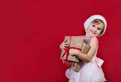 可爱的可爱的微笑女孩持有圣诞节礼物孤立的红色的