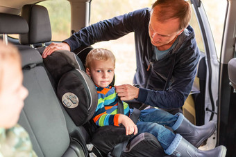 父亲紧固安全带婴儿男孩车座位
