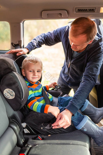 父亲紧固安全带婴儿男孩车座位