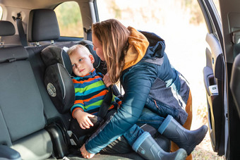 妈妈。紧固安全带婴儿男孩车座位