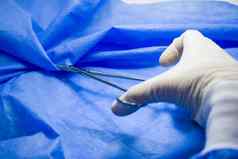 手术钳医生手蓝色的背景工作室拍摄操作设备手术过程