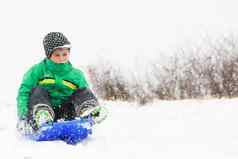 年轻的男孩显示兴奋滑雪橇山冬天