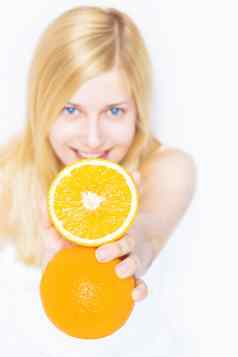 年轻的金发女郎持有橙色水果微笑健康的吃