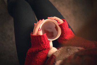 前拍摄女孩气候变<strong>暖茶</strong>喝手坐着沙发圣诞节彩色的指甲驯鹿毛衣