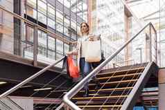 成人女人走楼梯购物购物中心携带色彩斑斓的购物袋