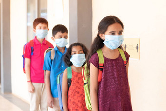 学校儿童站行前面类维护社会距离教室医疗面具穿概念科维德冠状病毒安全措施学校