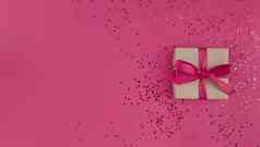 礼物盒子包装工艺纸粉红色的丝带弓五彩纸屑粉红色的背景单色节日平躺复制空间
