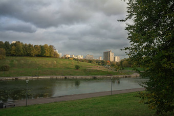 河路堤城市公园绿色草地大树灰色的重云天空高层建筑背景概念城市环境娱乐的地方大都市