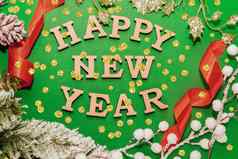 快乐一年庆祝活动木信一年的帽绿色背景红色的丝带黄金五彩纸屑云杉分支节日装饰明信片概念前视图平铺复制空间