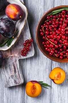 新鲜的甜蜜的李子水果切片板迷迭香叶子切割董事会红色的醋栗浆果