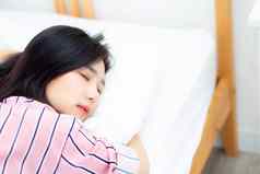 肖像美丽的亚洲年轻的女人睡眠说谎床上