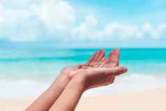 女人手的地方祈祷前面自然清洁海滩蓝色的天空