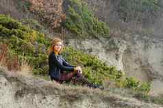 美丽的女孩秋天衣服坐在风景如画的的地方