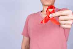 红色的艾滋病意识丝带持有男人。灰色背景世界艾滋病一天医疗保健医疗概念